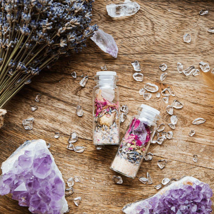 glass tubes filled with salts, lavender and crystal fragments, on a wooden table with amethyst and lavender.